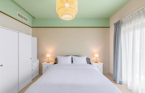 ein Schlafzimmer mit einem großen weißen Bett und zwei Lampen in der Unterkunft New fully serviced 2BR apartment in al-Ain