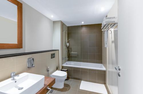 uma casa de banho com um lavatório, uma banheira e um WC. em New fully serviced 2BR apartment em Al Ain