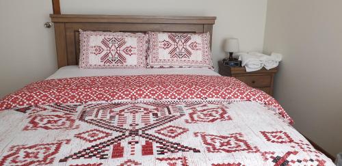 uma cama com um cobertor e almofadas vermelhos e brancos em Clayton Living Town House at Monash Doorstep em Clayton North