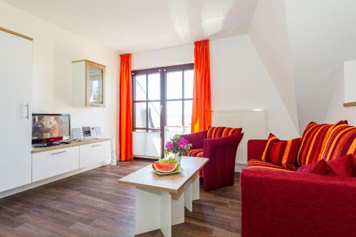 ein Wohnzimmer mit roten Sofas und einem TV in der Unterkunft Selliner Ferienappartements mit Balkon und Seeblick in Ostseebad Sellin