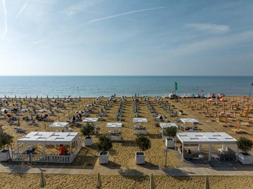 a beach with a lot of chairs and the ocean at Hotel Las Vegas in Bibione