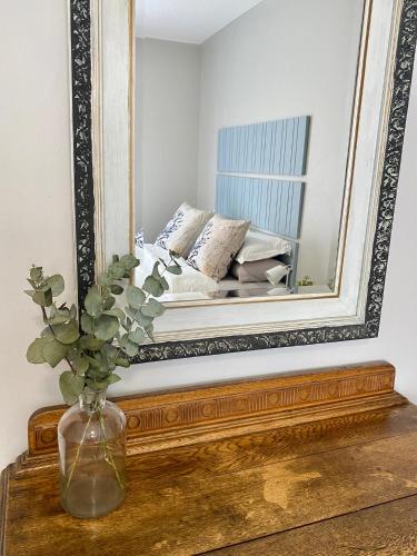 a mirror on top of a wooden table with a vase at Stay on Main in Paarl
