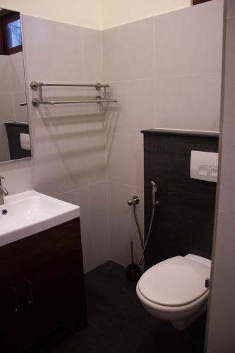 a bathroom with a white toilet and a sink at URALSURF HOUSE in Weligama
