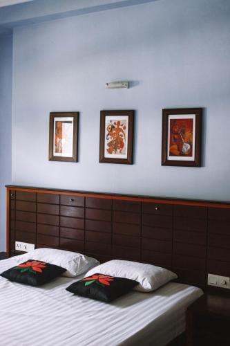 a bedroom with a bed with three pictures on the wall at URALSURF HOUSE in Weligama