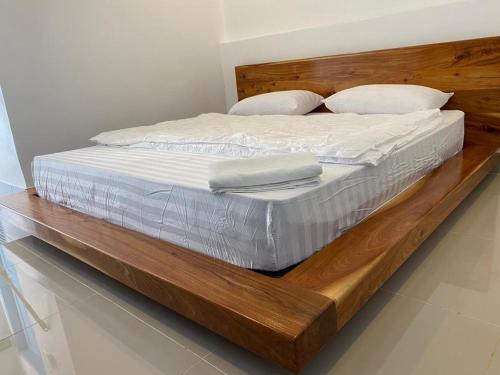 uma cama de madeira com lençóis brancos e almofadas em B2 Hotel Savannakhet em Savannakhet