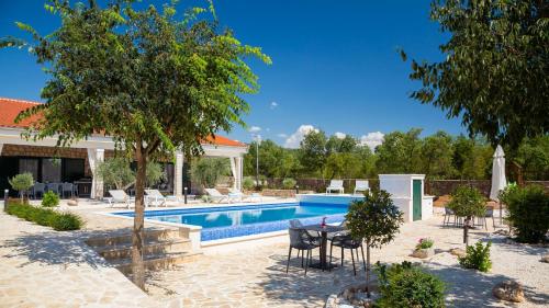 a swimming pool with chairs and a table in a yard at Tosic Estate - Villa, Vineyards and Winery in Razvođe