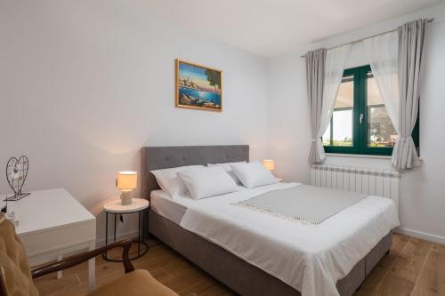 a white bedroom with a bed and a window at Tosic Estate - Villa, Vineyards and Winery in Razvođe
