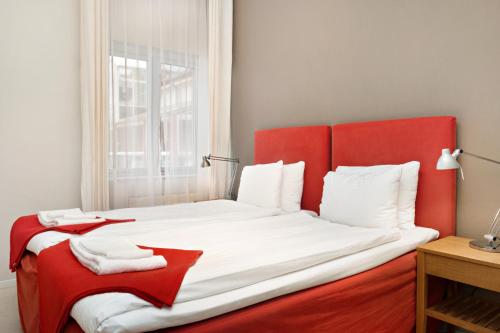 a red and white bed in a room with a window at Stadsparken Apartments in Helsingborg