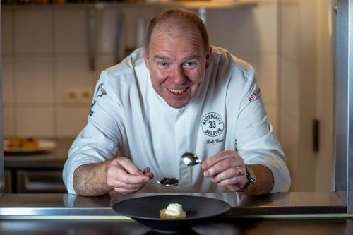 a man in a kitchen eating food with a spoon at Hotel Villa Select in De Panne