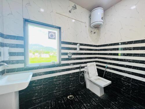 baño con aseo y lavabo y ventana en GREEN DANDI HOMESTAY en Rishīkesh