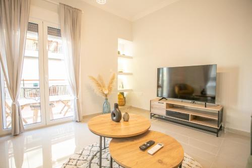 Modern and Luxury apartment في أثينا: غرفة معيشة مع طاولتين وتلفزيون بشاشة مسطحة