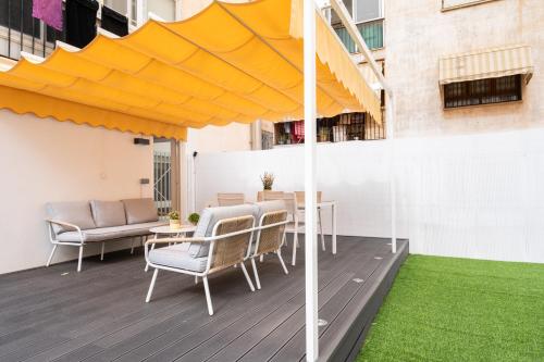 Apartamento Manola con terraza junto al Corte Inglés في البسيط: فناء مع طاولة وكراسي ومظلة صفراء