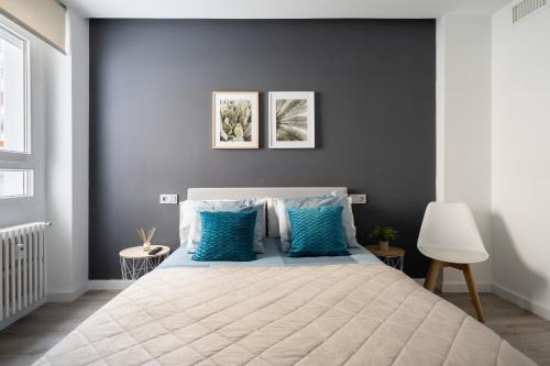 una camera da letto con un grande letto con cuscini blu di Apartamento Manola con terraza junto al Corte Inglés ad Albacete