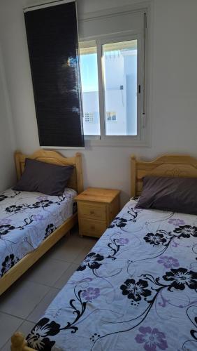a bedroom with two beds and two windows at Appt al hoceima pour les familles 3ème étage in Al Hoceïma