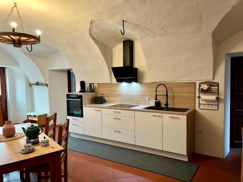 cocina con armarios blancos, fregadero y mesa en Ferienwohnung Mahar en Feistritz im Rosental
