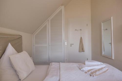a bedroom with a bed with white sheets and a window at Ostsee - Reetdachhaus Nr 42 "Waterkant" im Strand Resort in Heiligenhafen