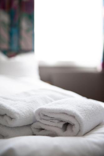 a pile of towels sitting on top of a bed at Henriks Hotell in Skien
