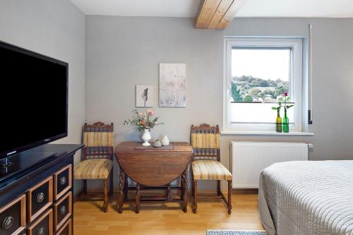 a bedroom with a dining room table with chairs and a television at Ferienhaus Cosyhome Vogelsberg in Köddingen