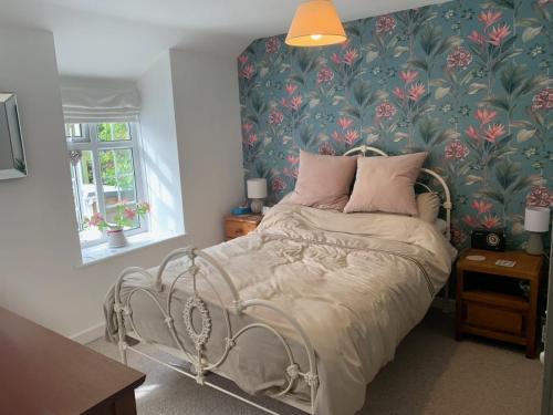a bedroom with a bed with a floral wallpaper at Character Cottage in Gunnislake in Gunnislake
