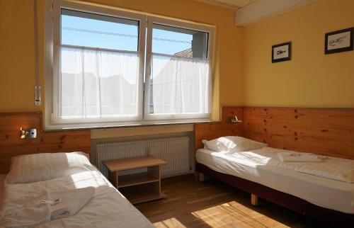 two beds in a room with a window at Pension-zur-Rose in Schönaich