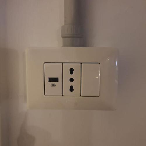 a white lightswitch with three switches on a wall at A casa di Marco in Canonica d'Adda