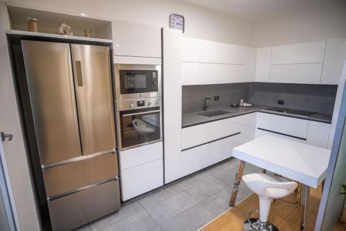 uma cozinha com armários brancos e um frigorífico de aço inoxidável em Casa Gioia em Nebbiuno