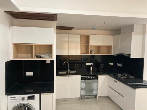 uma cozinha com armários brancos e bancadas pretas em Alfred apartments em Colombo