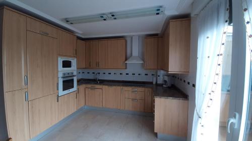 a kitchen with wooden cabinets and white appliances at Chalet Aia -Naturaleza y seguridad, entorno rural a 29 km de San Sebastian in Aia