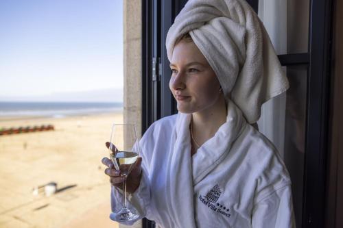 Eine Frau mit einem Handtuch auf dem Kopf mit einem Glas Wein. in der Unterkunft Hotel Villa Select in De Panne