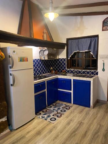 eine Küche mit blauen Schränken und einem weißen Kühlschrank in der Unterkunft Rural House to take a Break, La Serreria 25 in Tacoronte