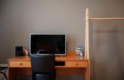 a desk with a television on top of a desk with a chair at Henriks Hotell in Skien