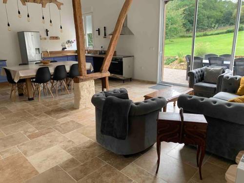 ein Wohnzimmer mit Sofas, einem Tisch und einem Esszimmer in der Unterkunft Gîte La Grange, Maison entière in Blicourt