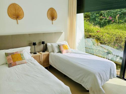 two beds in a bedroom with a window at Casa de la Risa - Sotogrande house with rooftop pool in San Enrique de Guadiaro