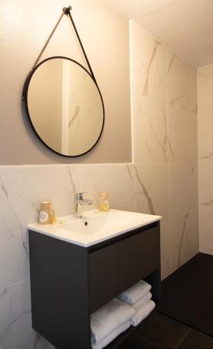 une salle de bain avec un lavabo et un miroir dans l'établissement Hôtel des Pins, à Jullouville