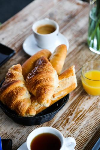 une table avec une assiette de pain et une tasse de café dans l'établissement Hôtel des Pins, à Jullouville
