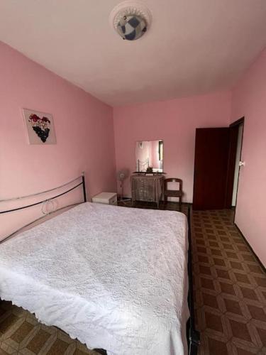 1 dormitorio con 1 cama blanca en una habitación rosa en Affittacamere di Dani, en Spianate
