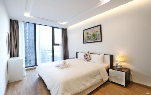 a bedroom with a white bed with a teddy bear on it at QMP - Vinhomes Metropolis in Hanoi
