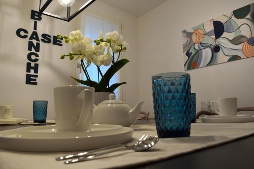 a table with a plate and a vase with white flowers at B&B Case Bianche in Maranello