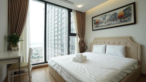 a bedroom with a white bed and a large window at QMP - Vinhomes Metropolis in Hanoi