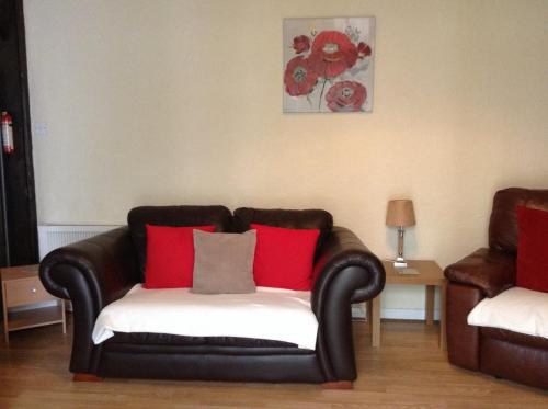 a black couch with red pillows in a living room at Darroch View Cottage in Invermoriston