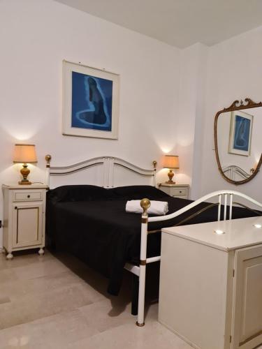 Schlafzimmer mit einem schwarzen Bett und einem Spiegel in der Unterkunft Tiny Apartment Vitty - San Martino Buon Albergo Verona in San Martino Buon Albergo