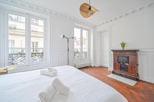 a white bedroom with a bed and a fireplace at Le Ruby D'Hauteville - Coeur de Paris - Unique - Spacieux 6 couchages in Paris