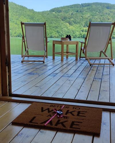 two chairs and a table on a wooden deck at Splav Wake at the lake in Gaočići