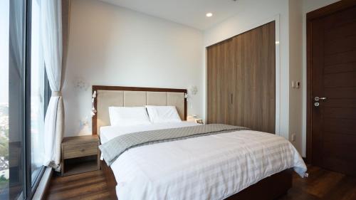 a bedroom with a bed with white sheets and a window at QMP - Vinhomes Metropolis in Hanoi