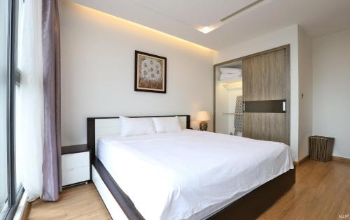 a bedroom with a large white bed and a window at QMP - Vinhomes Metropolis in Hanoi