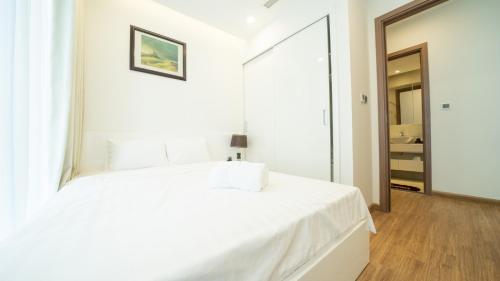 a bedroom with a white bed with a large mirror at QMP - Vinhomes Metropolis in Hanoi