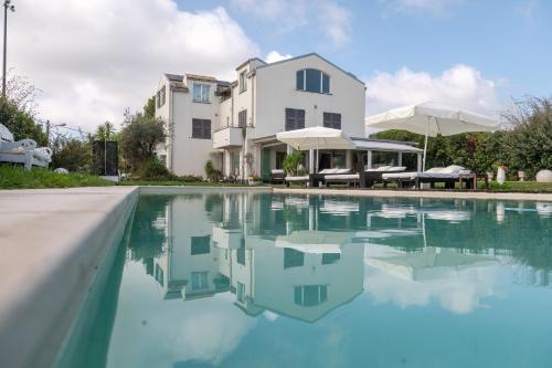 a house with a swimming pool in front of a building at Villa VERNEY in Albisola Superiore