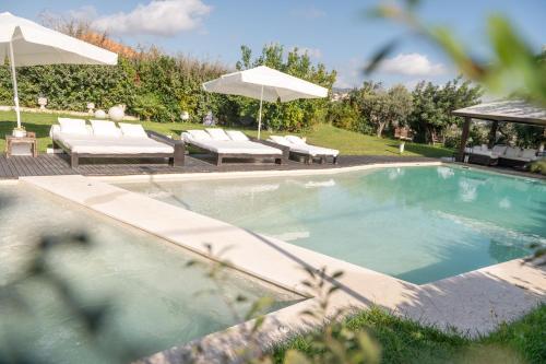 a swimming pool with chairs and umbrellas in a yard at Villa VERNEY in Albisola Superiore