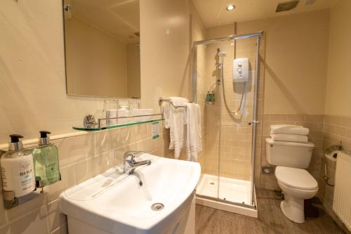 a bathroom with a sink and a shower and a toilet at The Abbey Inn in Paisley