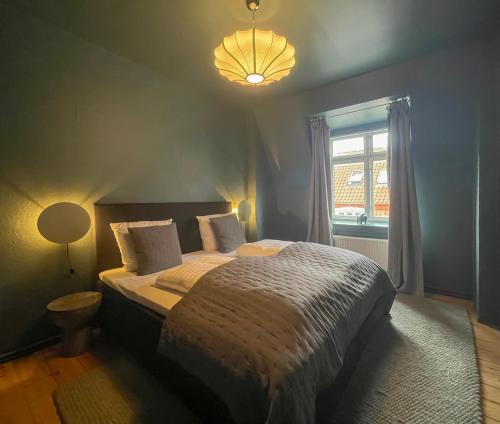 een slaapkamer met een bed, een lamp en een raam bij Rustic & Cozy 2BR in Heart of CPH City by Strøget in Kopenhagen